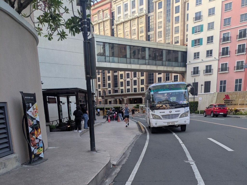 Newport Cityのバス停留所と「BACLARAN - NICHOLS」表示のローカルバス